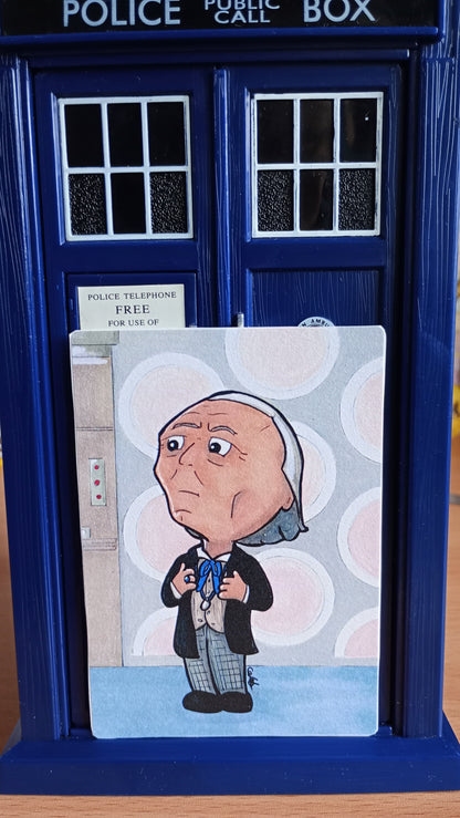 Large rectangular sticker with a picture of a Chibi Doctor Who drawing, set in front of a toy TARDIS 